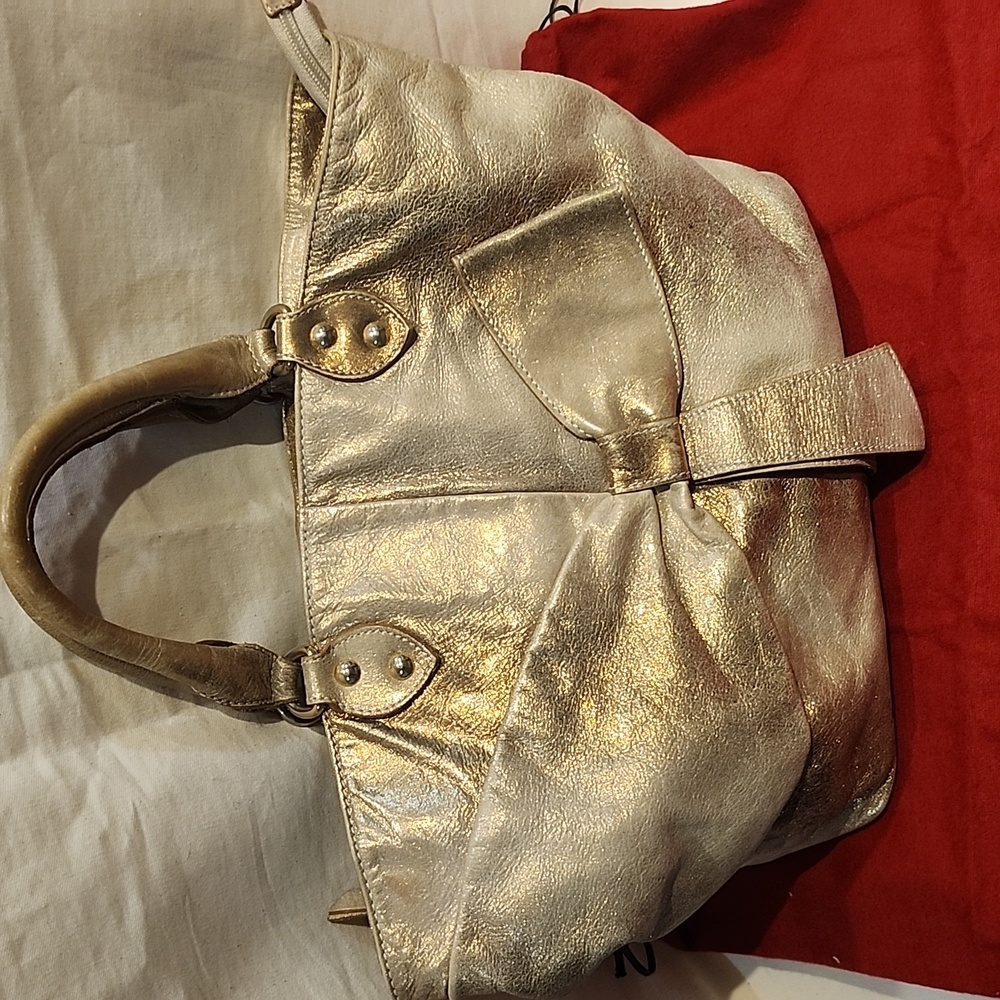 Valentino Garavani metallic in two-tone  light gold bow in front of the bag